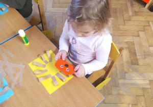 Dziecko nakleja szablon jeża na karton